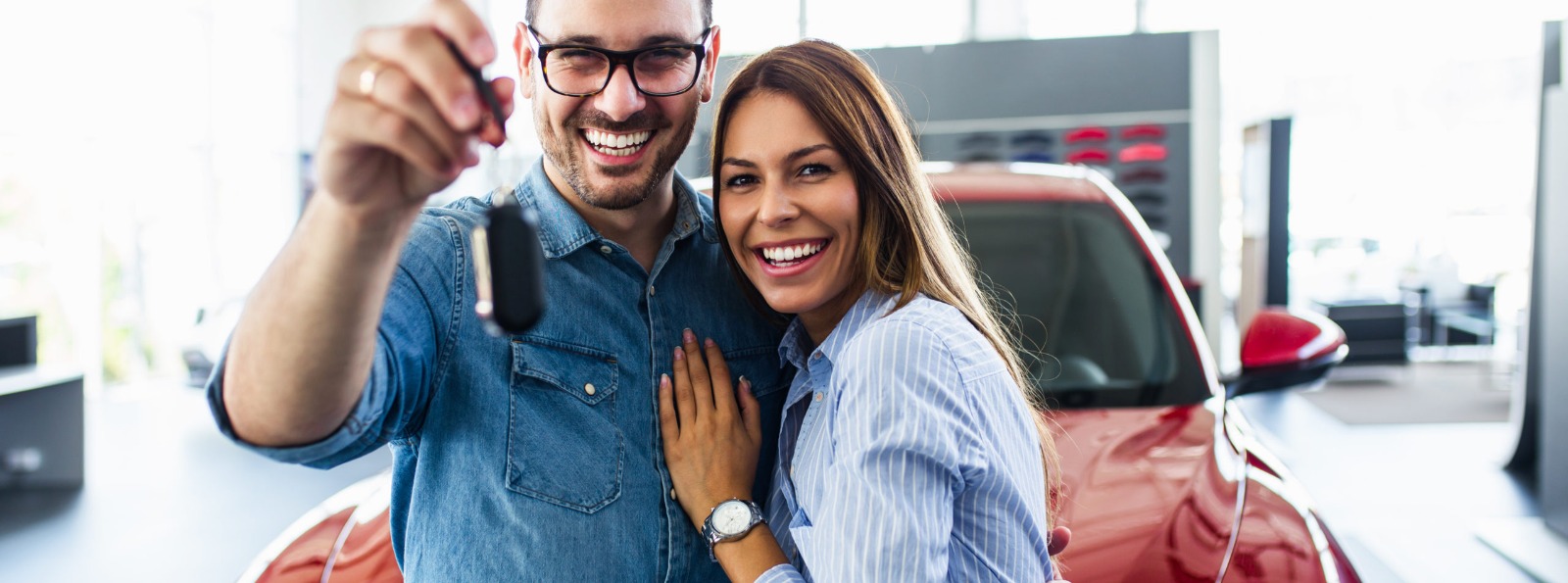 a couple holding key to a new vehicle