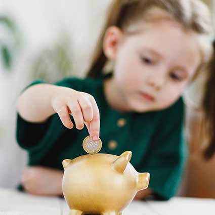 Little girl saving money in a piggy bank