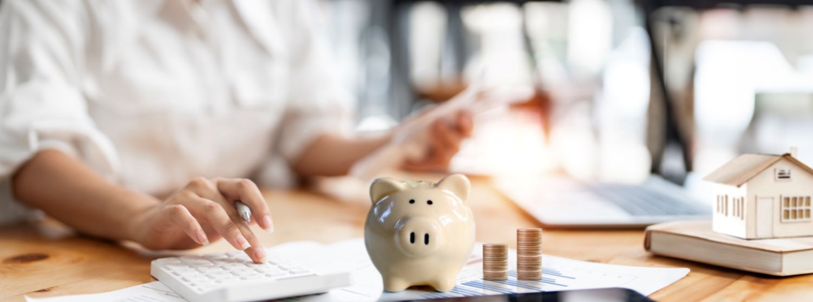 a person calculating their home finances with a cream piggy bank