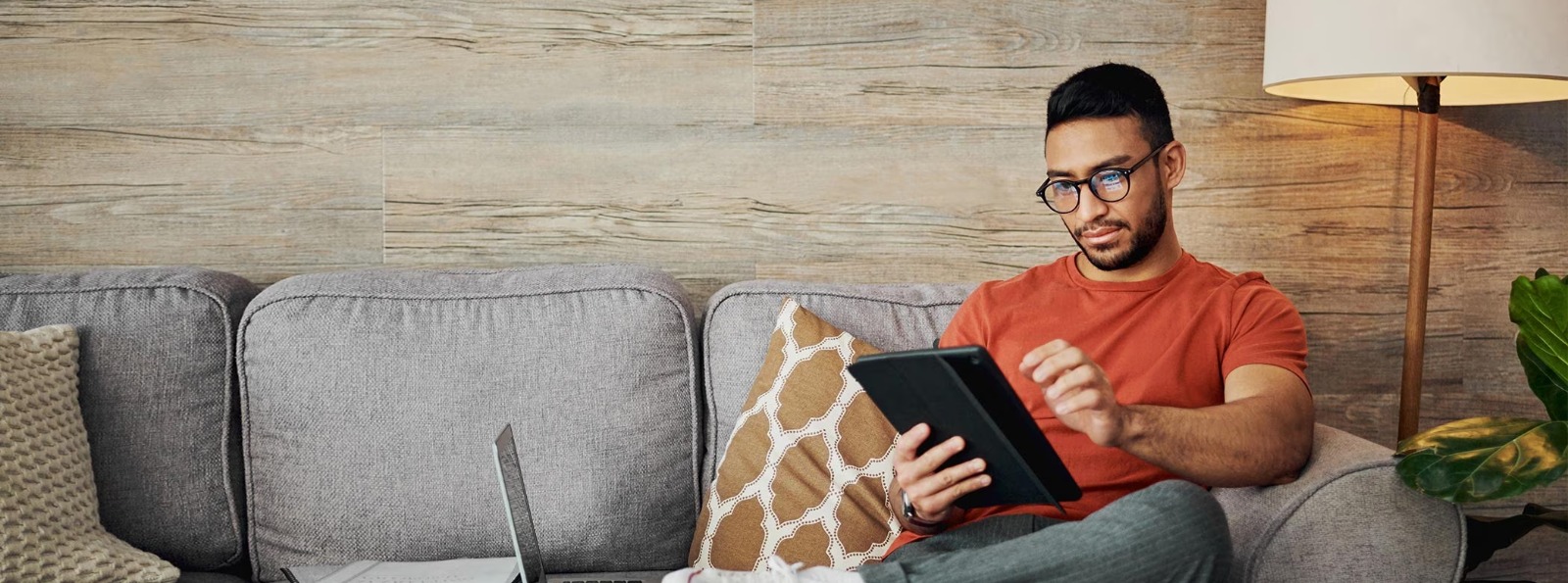 man sitting on a couch reading his tablet
