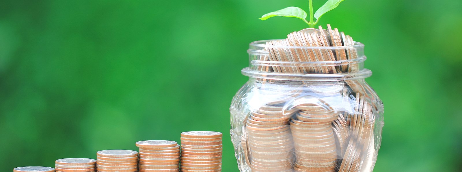 a stack of coins next to a glass jar of coins