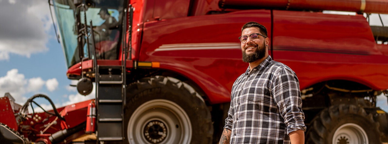 a person walking besides a red combine