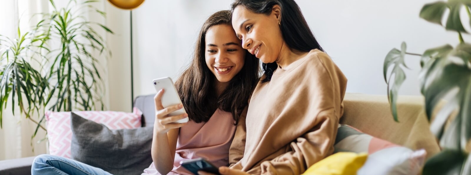 a mother and child sitting on a couch looking a mobile phone
