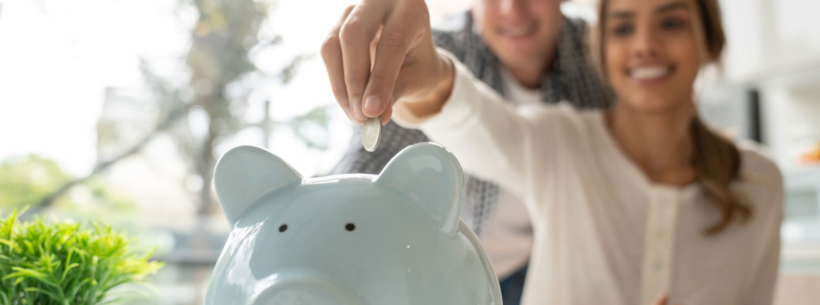 a couple putting coins in a blue piggy bank