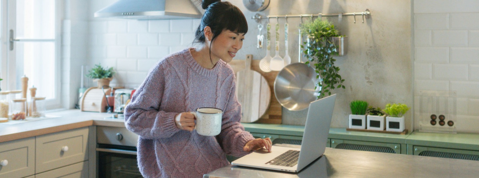a woman in her kitchen on her laptop computer
