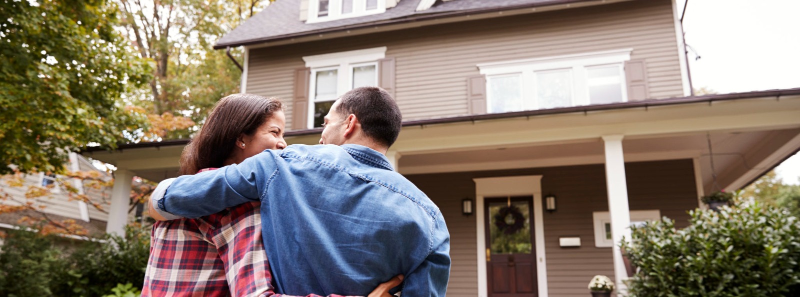 a couple standing in front of their new home